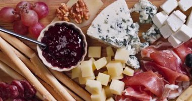 Ahşap kesim tahtasının üzerinde çeşitli et ve peynir aperatifleri, yakın çekim şarküteri parti için servis edilir.