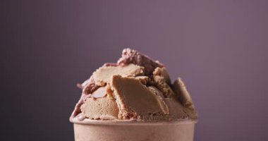 Çikolata ve fıstık dondurması kağıt bardakta dönüyor, yemekler mor arka planda kapanıyor.