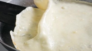 Aşçı kızartma tavasında krep çevirir. Mutfaktaki sıcak tavada taze pişmiş krep yakın plan. Sağlıklı kahvaltı için evde leziz krep yapma süreci, yiyecek kapanıyor.