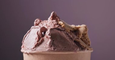 Çikolata ve fıstık dondurması kağıt bardakta dönüyor, yemekler mor arka planda kapanıyor.