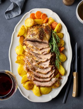 Gri masada taze pişmiş domuz eti rostosu ve sebzeler.