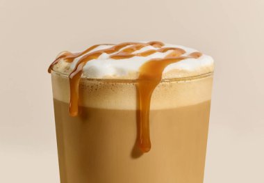 Bej arka planda karamel latte bardağına yakın plan.