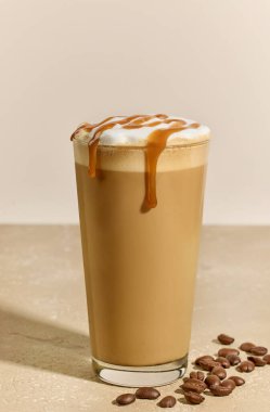 Bej arka planda karamel latte bardağına yakın plan.