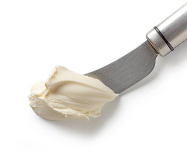 Beyaz arka planda izole edilmiş bıçağın üzerindeki taze krem peynir.