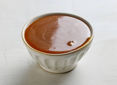 Beyaz mutfak masasında bir kase taze karamel sosu