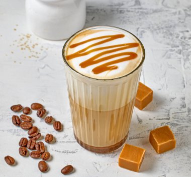 Beyaz masa arkasında karamel latte bardağına yakın plan.