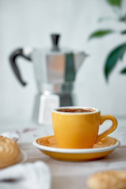 Sarı kahve fincanı ve kahve demliği bej mutfak masasında, seçici odaklı.