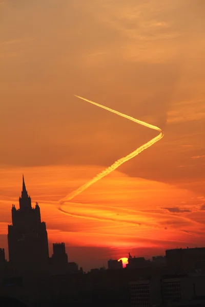 Trace of the plane. Dawn. City. — Stock Photo, Image