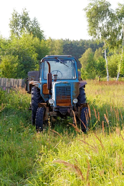 Tractor de ruedas viejo con el remolque contra madera — Foto de Stock