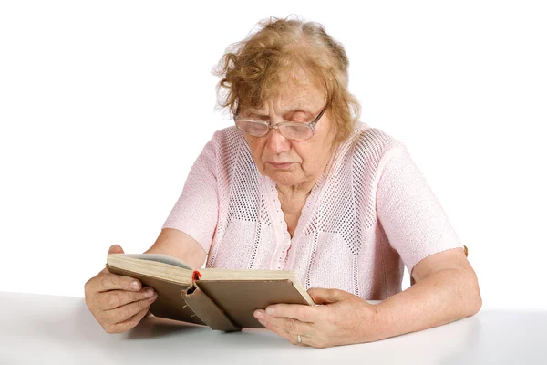 Mulher velha em óculos lê o livro em um fundo branco — Fotografia de Stock