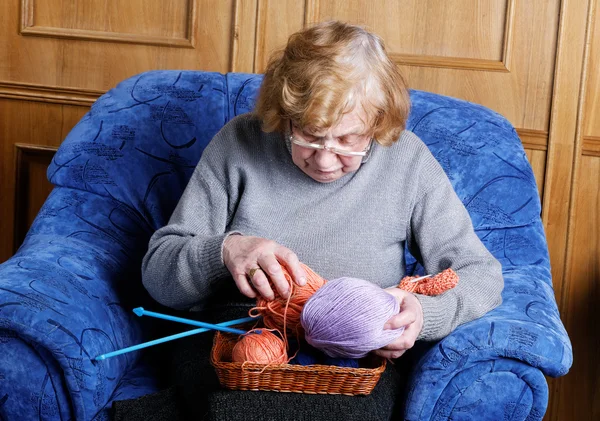 Grandmother in a chair with a thread for knitting — Stock Photo, Image