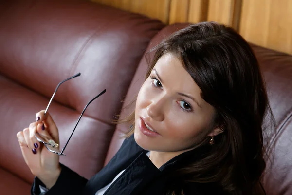 The girl in a suit sits on  leather sofa — Stock Photo, Image