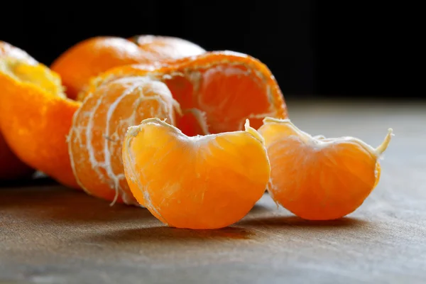 Peeled tangerines with slices on a black background — Stock Photo, Image