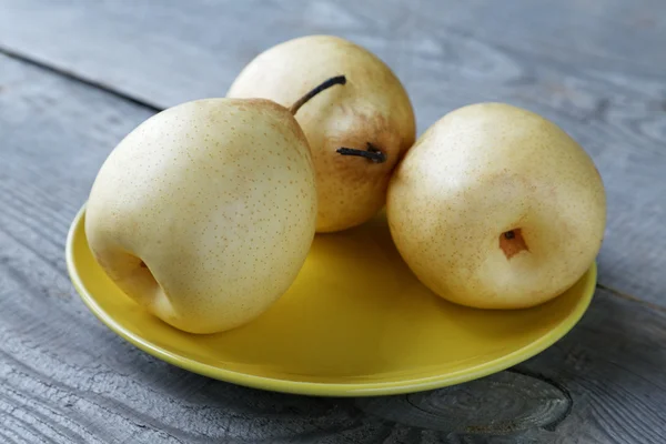 Yellow pears on the plate on a rustic table — Stock Photo, Image