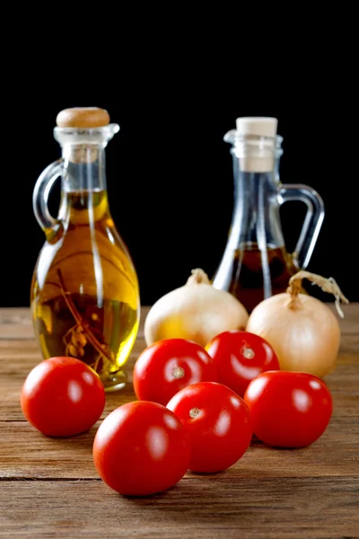 Tomatoes and bottles of olive oil on rustic table — Stock Photo, Image