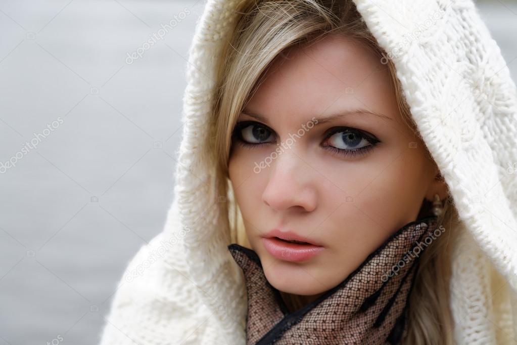 The thoughtful girl in  knitted dress on a background of water