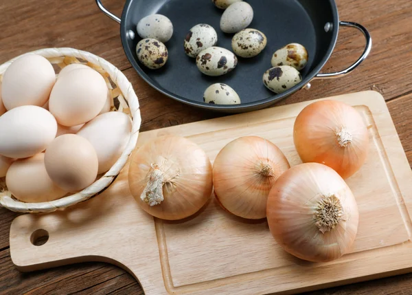 Натюрморт з цибулею та перепелиними яйцями на кухонному столі — стокове фото