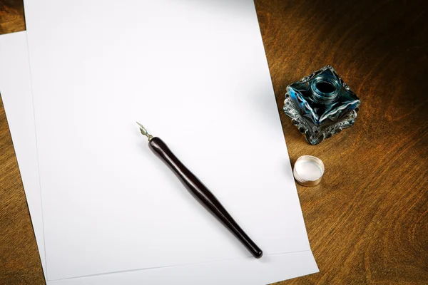 Δοχείο μελανιού και πένα με φύλλα χαρτιού σε ένα τραπέζι — Φωτογραφία Αρχείου