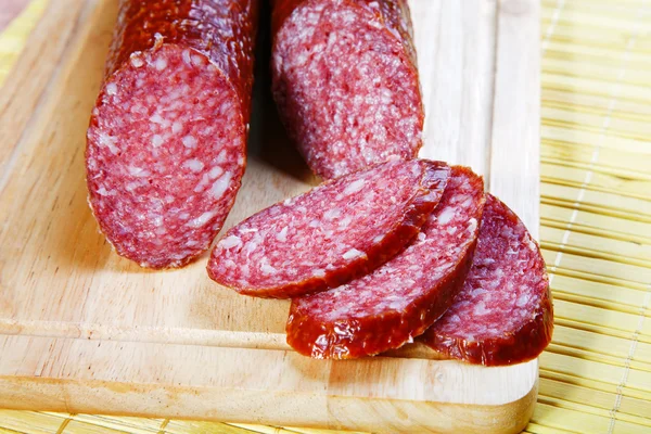 La salchicha ahumada cortada en una tabla de madera — Foto de Stock