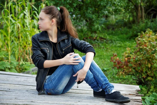 The girl sitting on wooden boards in a summer garden Stock Picture
