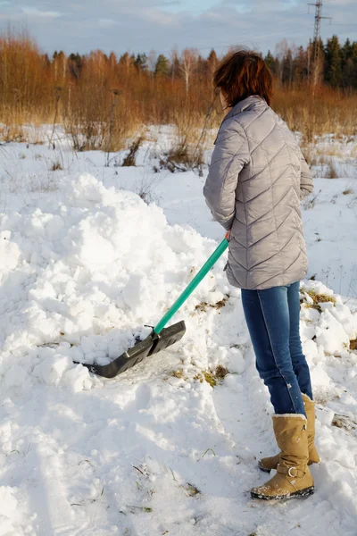 A mulher limpa a neve uma pá — Fotografia de Stock