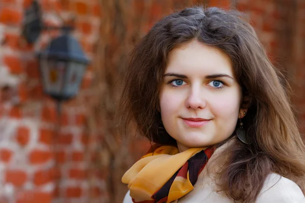 De lachende meisje tegen een bakstenen muur — Stockfoto