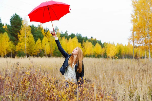 La ragazza con un ombrello rosso nel parco autunnale — Foto Stock