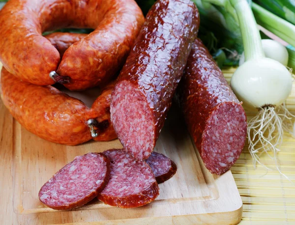 Still-life with smoked sausage and an onions on a kitchen table — Stock Photo, Image
