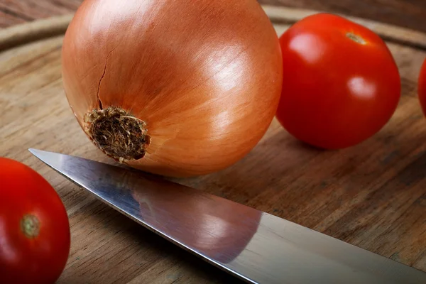 La cebolla los tomates y el cuchillo a la tabla de cortar — Foto de Stock