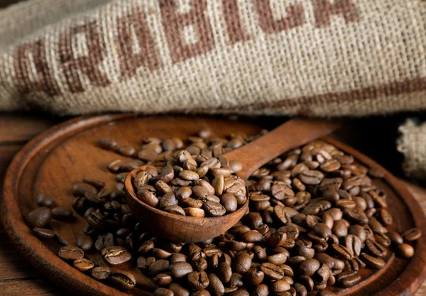 Koffie bonen met een jute en houten lepel — Stockfoto