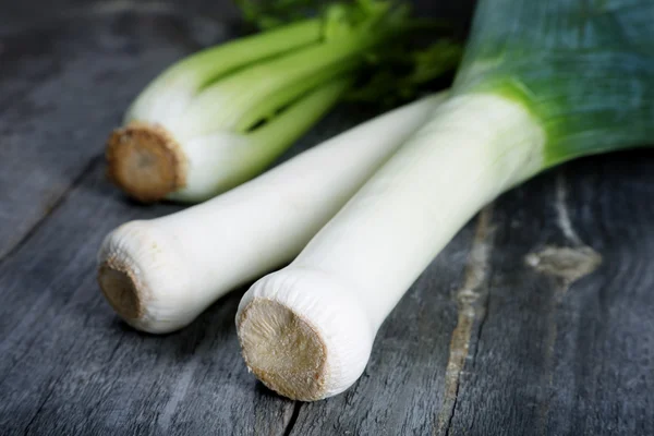 Grote sjalot stengels op een rustieke tafel — Stockfoto