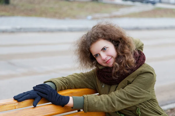 Mädchen träumt im Herbst auf einer Straßenbank — Stockfoto