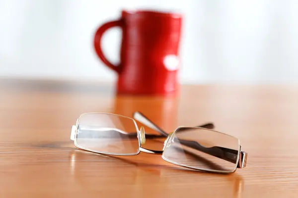 Stilleben med glasögon och en röd kopp — Stockfoto