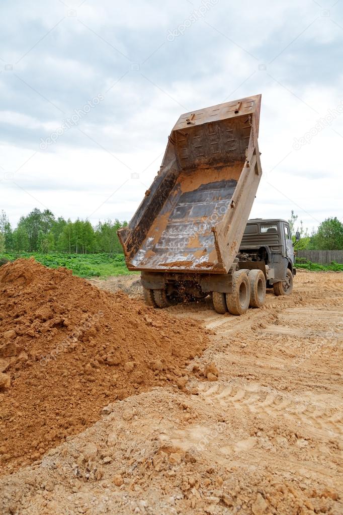 dump-body truck unloads a ground on the land