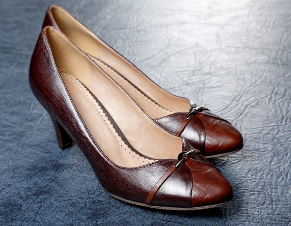 Sapatos femininos marrons contra de um couro — Fotografia de Stock