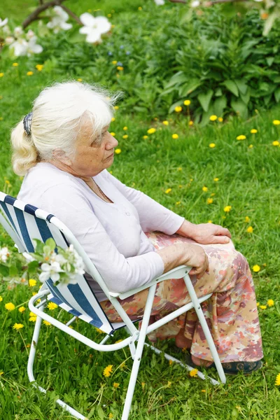 La nonna in giardino sotto un melo fiorente — Foto Stock