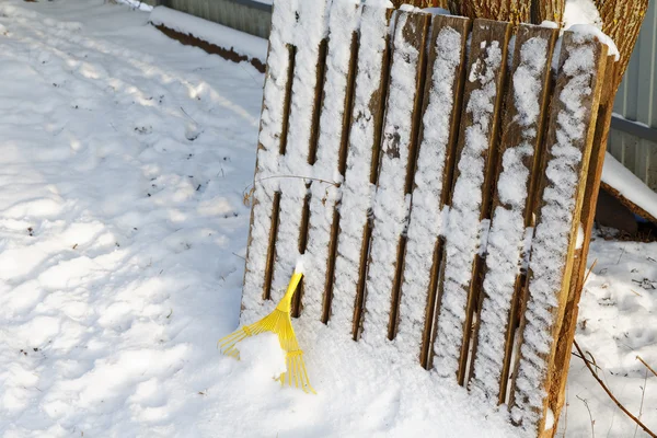 Yellow rake under snow in winter day — Stock Photo, Image