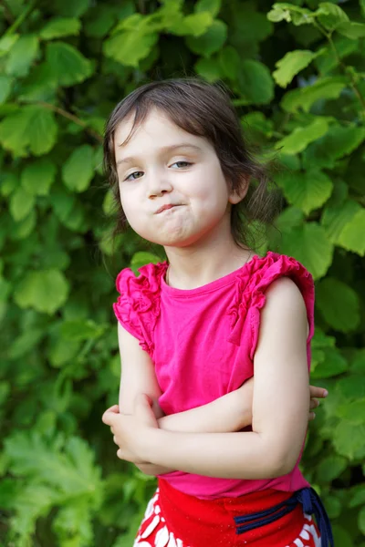 Bambina sorridente su uno sfondo di foglie verdi — Foto Stock