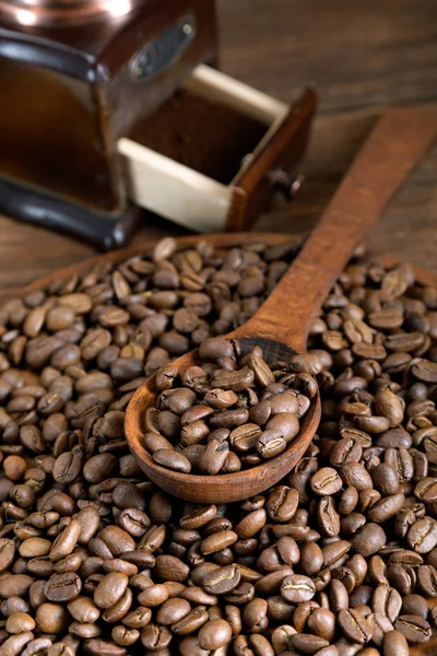 Grinder and coffee beans with a wooden spoon — Stock Photo, Image
