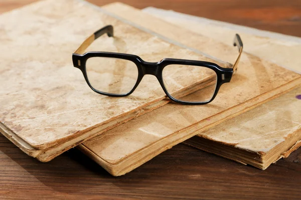 Vecchi libri di scrittura e occhiali su un tavolo di legno — Foto Stock