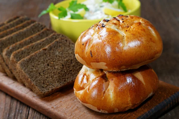 Plaat met sla en brood rollen aan de tafel dorp — Stockfoto