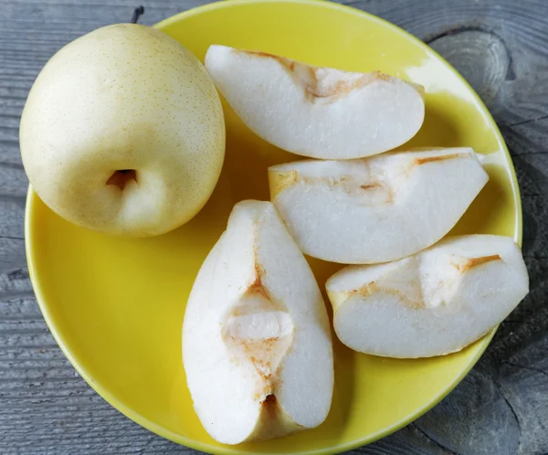 Gele peren in een kom op een rustieke tafel gesneden — Stockfoto