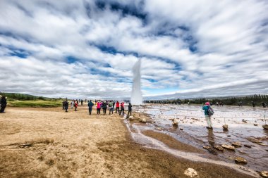 Icelandic geyser surrounded by tourists  clipart
