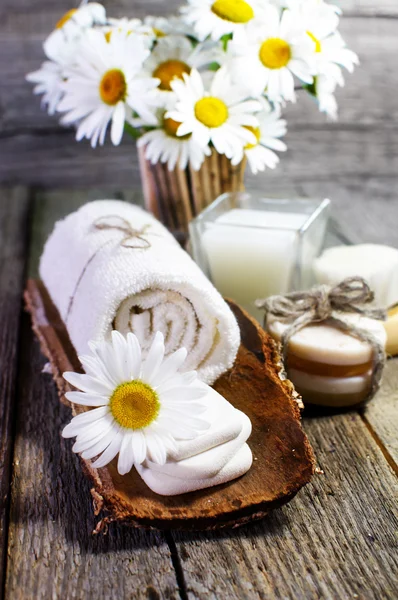 Margaridas bonitas, vela, óleos aromáticos e outros acessórios spa na superfície de madeira . — Fotografia de Stock