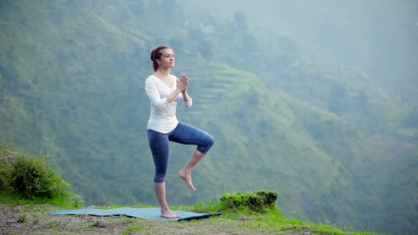 Woman doing yoga asana tree pose outdoors — Stock Video