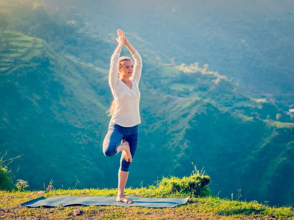 Woman doing yoga asana Vrikshasana tree pose in mountains outdoors — Stock Photo, Image