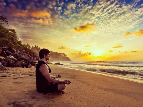 Jonge sportieve passen man doen yoga mediteren op tropisch strand — Stockfoto