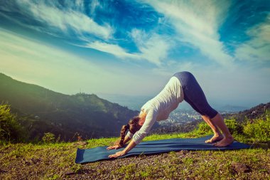 Genç, formda bir kadın dağlarda yoga yapıyor.