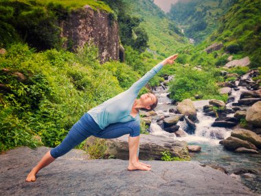 Kadın yoga yapıyor. Utthita Parsvakonasana açık havada.