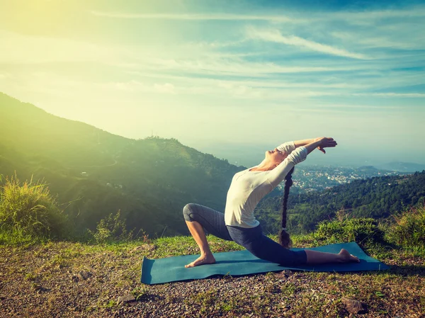 Sporty fit woman practices yoga Anjaneyasana in mountains — Stock Photo, Image